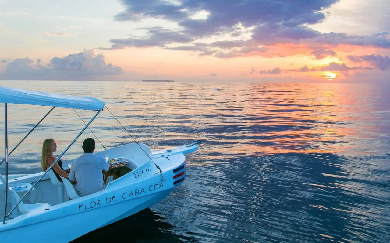 A couple on a boat at sunset in the ocean.