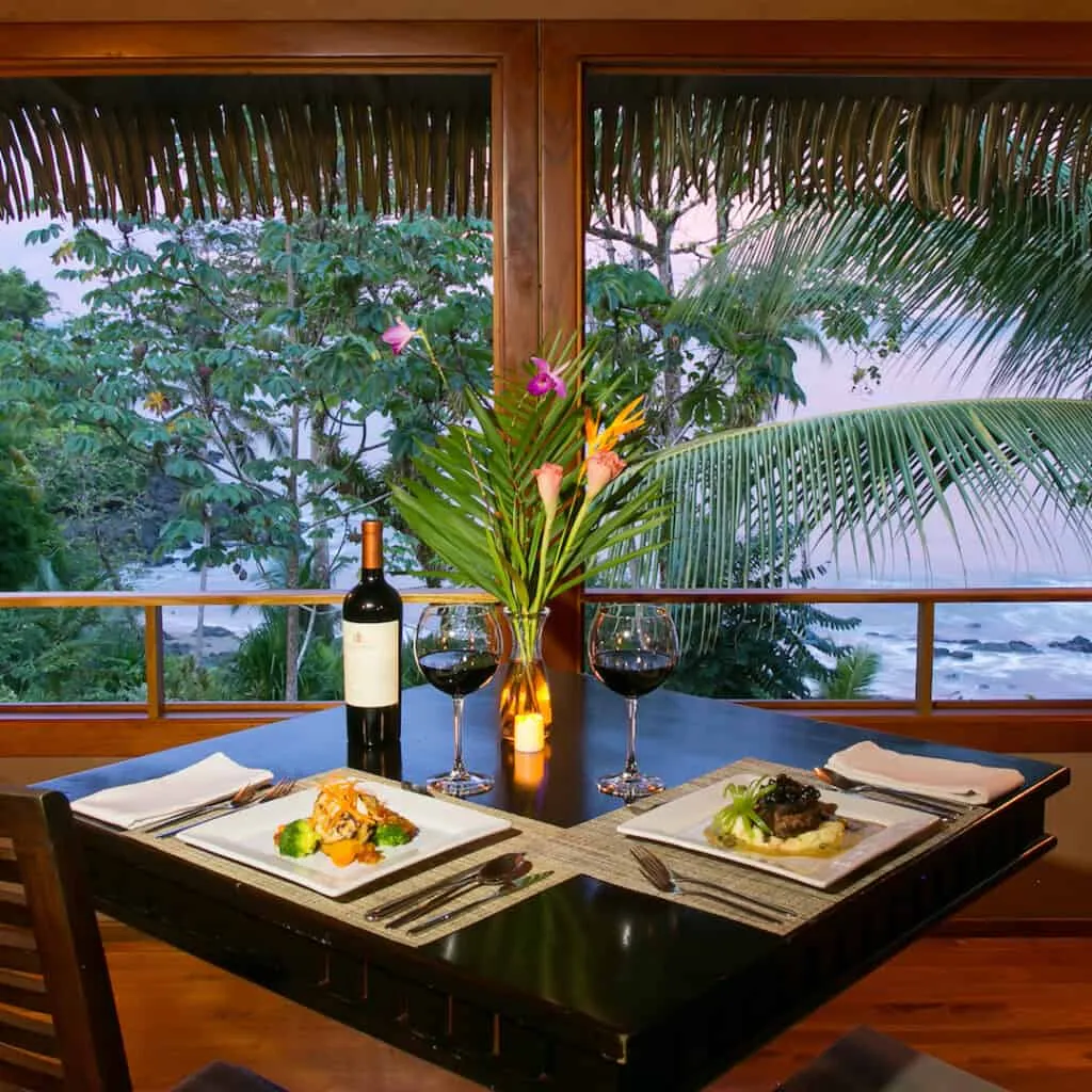 A table with two plates and a bottle of wine.