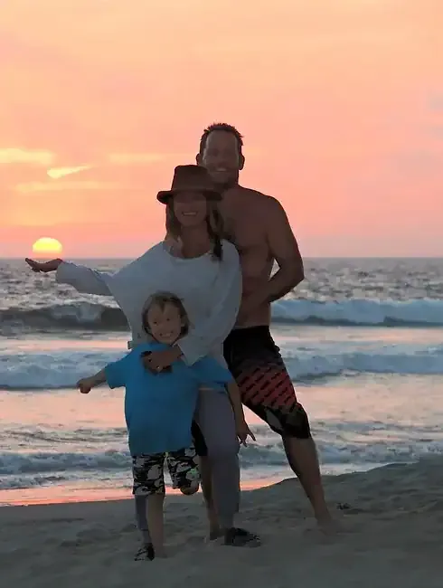 A man and woman standing on the beach at sunset.