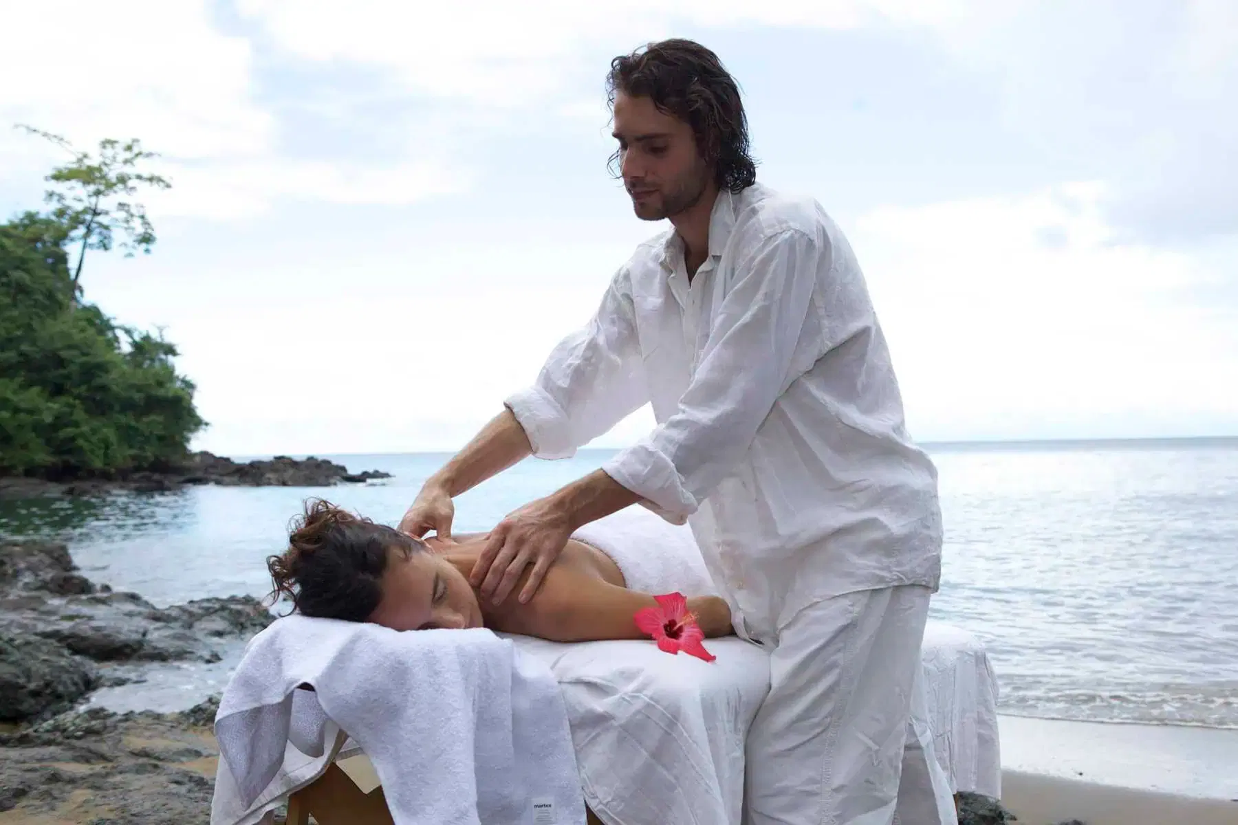 A man getting a massage on the beach.